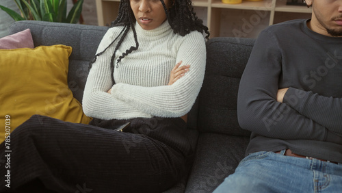 A man and woman in a disagreement sitting apart on a sofa showing tension and unhappiness in a home setting.