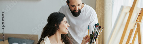 joyous husband helping his inclusive beautiful wife on wheelchair to paint on easel, banner