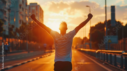 Energetic young adult celebrating victory at sunset on city street, motivational success theme, warm tones, silhouetted against golden hour sky.
