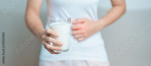 Lactose intolerance and Milk allergy concept. woman hold Milk glass and having abdominal cramps and pain when drink Cow Milk. Symptom stomach ache, Dairy intolerant, Nausea, Bloating, Gas and Diarrhea