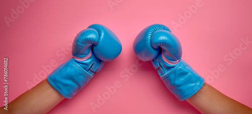 Blue boxing gloves ready for a fight against pink background