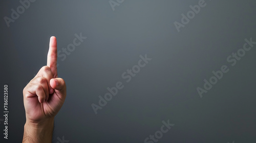 A hand with a raised index finger on a gray background, directing a close-up gesture