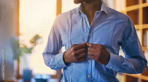 A person buttoning up a shirt before heading to work. 