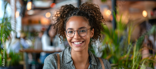 A woman with curly hair and glasses is smiling at the camera