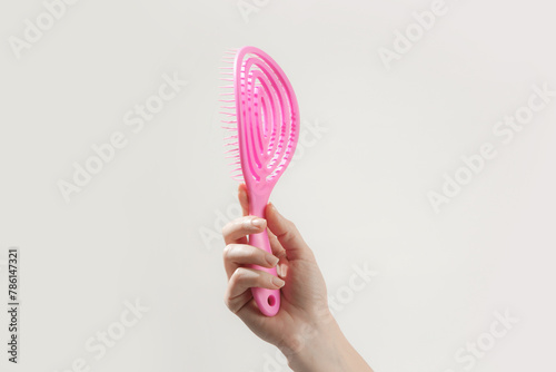 Young woman holding pink detangler hair brush, studio shot