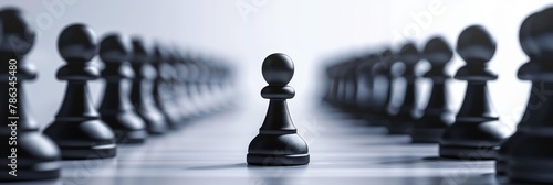 A lone black pawn stands in focus against a blurred backdrop of numerous pawns showcasing concepts like leadership and courage