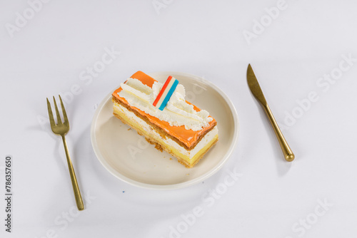 Dutch Oranje tompouce Cake with dutch flag on a white plate with gold cutlery for Kings Day