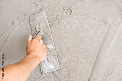 Hand plasterer plastering trowel wet cement house wall background 