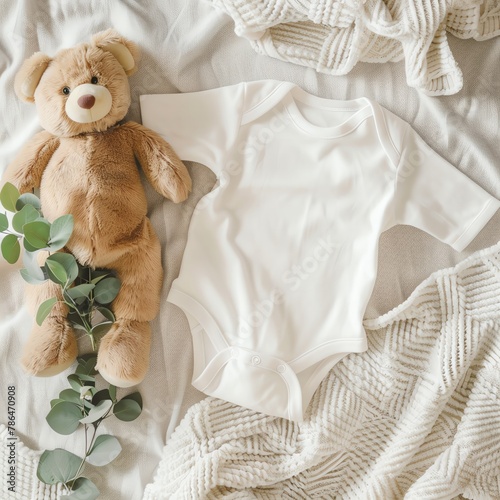 White cotton baby bodysuit with short sleeves, accompanied by a plush teddy bear and a fresh eucalyptus branch, arranged on an ivory white blanket, top view. Ideal for a mockup template, shot from DSL