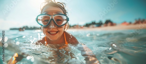 Cute little girl in a swimsuit wearing a mask and snorkel having fun playing in water at the beach. child in mask and snorkel on the beach in the water