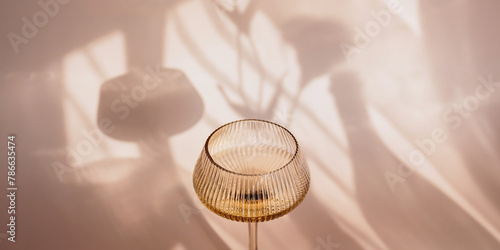 Two glasses with white wine placed on light beige background with shadows