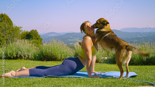 Lady in sportswear is exercising outdoors when her cute dog joins her with a toy