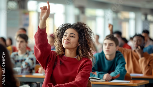 Curly teenage girl raises hand in classroom full of students. She looks engaged, eager to participate in discussion. Diverse group of students in background adds to educational atmosphere of scene