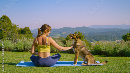 Brown mixed breed dog licks young lady on her face while she tries to do yoga