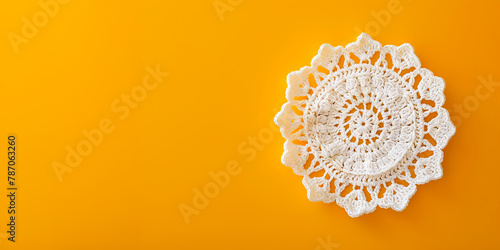 A white crochet doily on a yellow background.