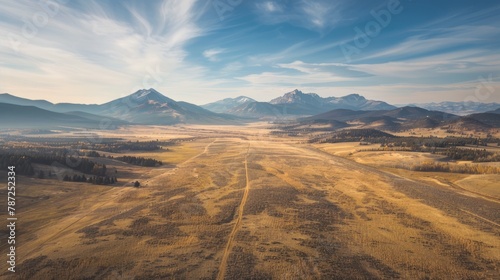 An expansive aerial shot capturing a dirt road winding through mountains in a conservation easement