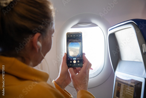 woman taking photos through plane window