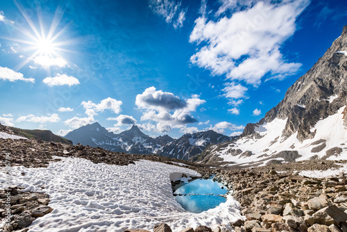 turquoise mountain lake surrounded by high alpine scree and snow fields