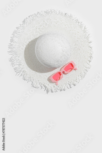 White sun hat and pink colored glasses on white background. Summer vacation, summertime relaxation concept, minimal trend flat lay Two colors photo Top view wide-brimmed hat and sunglasses