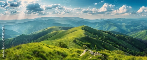 Beautiful spring landscape with green grass on the hill and mountains in background. Panoramic view of Carpathian mountain range