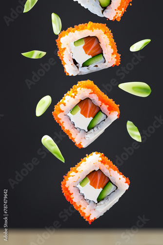 Delicious sushi on a dark background. Flying sushi on a black background. Tasty sushi in the air. Sushi Filadelfia. Sushi maki.