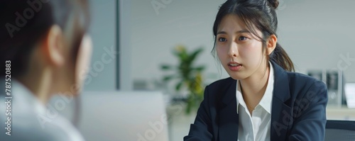 A Japanese woman in her late thirties is sitting at a desk having an interview with another Japanese businesswoman, doctors with patient consultations, healthcare and medical services.