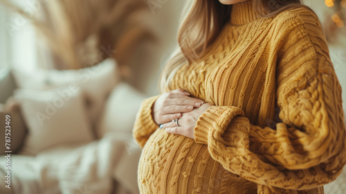 A woman expecting a child, hugging her stomach with her hands. A soft image of an expectant mother in a winter sweater.