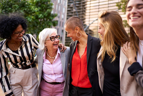 Meeting of diverse group of professionals business women in formal suit standing outdoors in front of an office building, sharing conversation and gesticulating in a financial center about matters