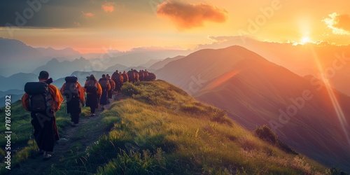 A group of people are walking up a mountain. The sun is setting in the background, casting a warm glow over the scene. The hikers are carrying backpacks and seem to be enjoying the beautiful view