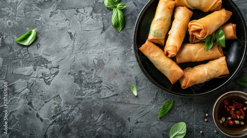 Tasty fried spring rolls on a grey surface from above with space for writing