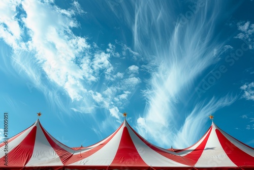 Blue and white circus tents with stars under a sunny sky with clouds