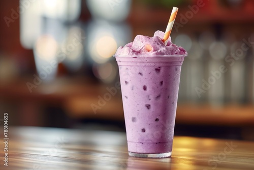 Iced purple drink taro iced milk tea in a clear cup on a bar, with a blurred background