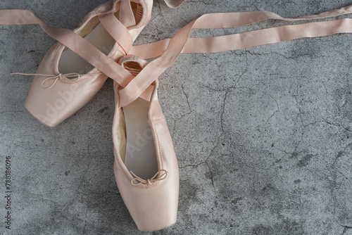 A pair of pink ballet slippers with a ribbon tied to the toe