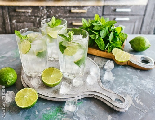 Bezalkoholowe mojito. Szklanki z orzeźwiającym napojem z limonką, miętą i kostkami lodu stojące na kuchennym blacie