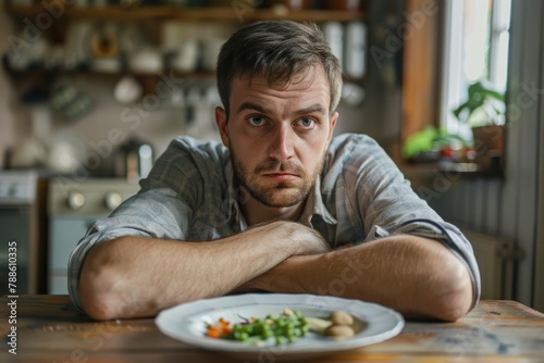 Loss of Appetite - Portrait of Depressed Caucasian Man with Aversion to Diet in Front of Dinner Plate, Concept of Anxiety and Appetite Suppressant