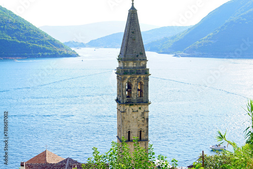 The most famous landmark of the Montenegrin city of Perast - the bell tower of the Church of St. Nicholas against the backdrop of the sea and mountains.