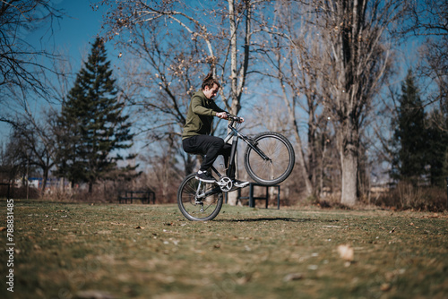 A dynamic scene of a young man effortlessly performing a wheelie on his bicycle in a beautifully lit park, capturing a moment of joy and freedom.