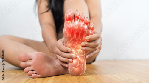 Painful and inflamed gout on foot. A woman with red feet is sitting on the floor.