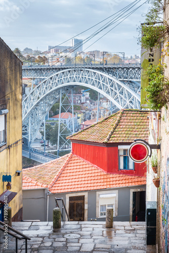 Street view of the narrow cobblestone streets of Porto with its old buildings and the Dom Luís I Bridge. Fragment of a metal railroad bridge, Portugal.