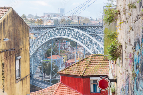 Street view of the narrow cobblestone streets of Porto with its old buildings and the Dom Luís I Bridge. Fragment of a metal railroad bridge, Portugal.