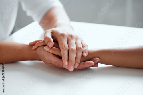 Hands, support and hope for console or care on table, comfort empathy for bad news or illness. Closeup, people and unity in crisis by prayer, trust or bond for person suffering with diagnosis