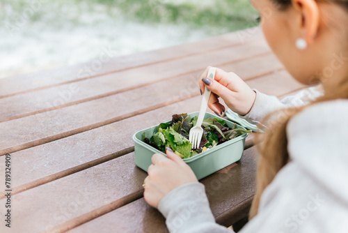 Hiker rests in a picnic area eating a tupperware with salad