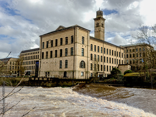New Mill Saltaire which was built in 1868 on the site of an earlier mill overlooking the weir on the River Aire and includes an Italianate chimney is now used as flats and by the NHS as offices
