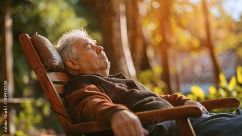 Senior old man sleeping on a wooden chair in front of the house, relaxing and enjoying, garden resting outdoors on a sunny day. Elderly pensioner retirement lifestyle, grandfather napping comfortable