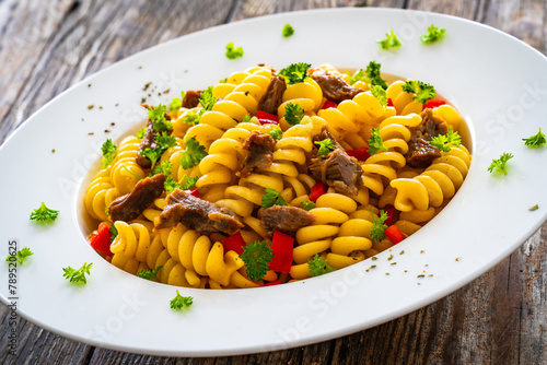 Pasta with roasted pork meat - noodles witch pork cheeks and vegetables on wooden background 