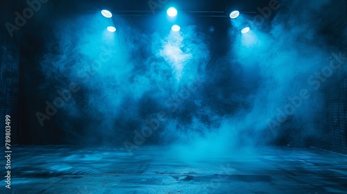 Blue spotlights illuminate an empty stage covered in fog.