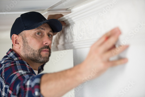 male decorator working on ceiling cornice