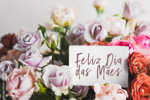 white card for a bouquet with the inscription Happy Mothers Day in Portuguese in a bright beautiful bouquet of flowers roses