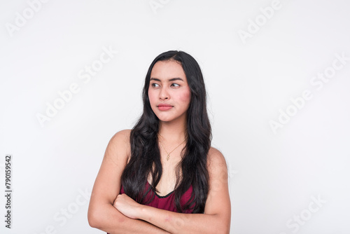 Young asian lady in maroon dress looking away, arms crossed in a gesture of refusal