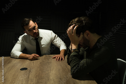 Focused detective interviews a distressed man in a dimly lit interrogation room